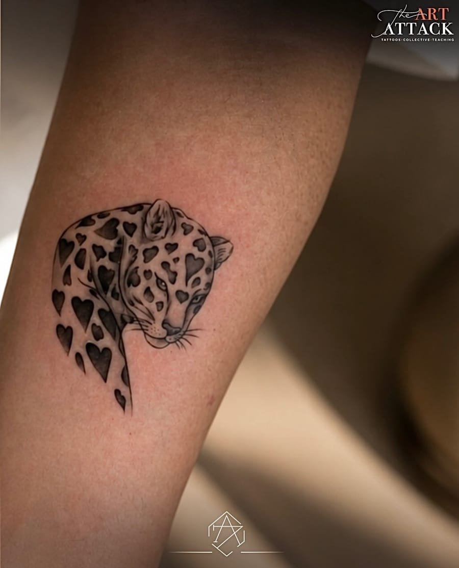 Black and grey leopard portrait tattooed on a forearm.